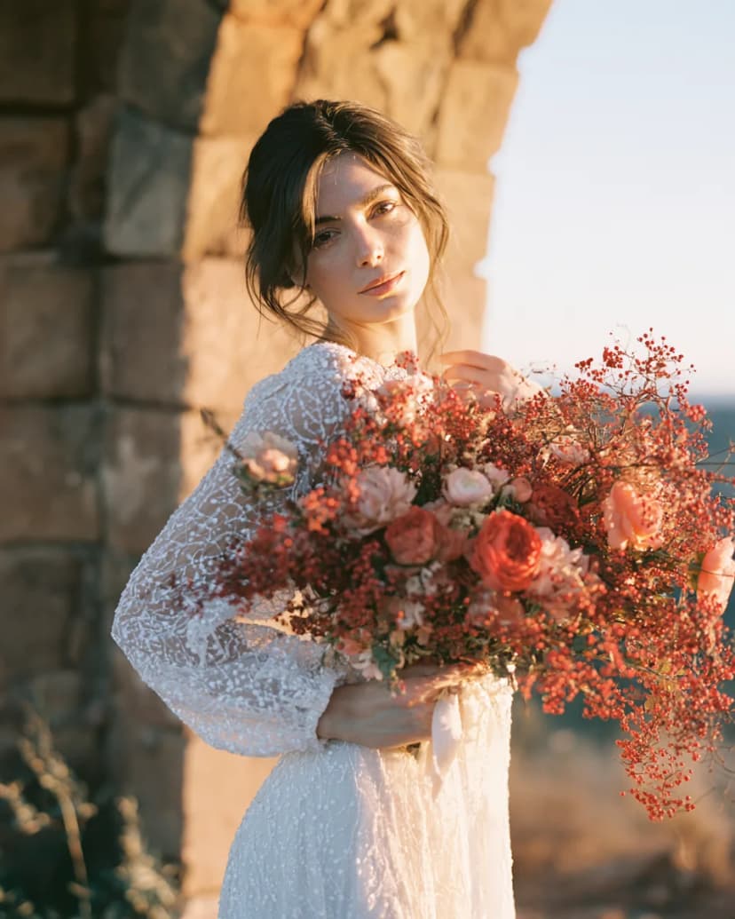 A bride with her bouquet of coral roses and berries.